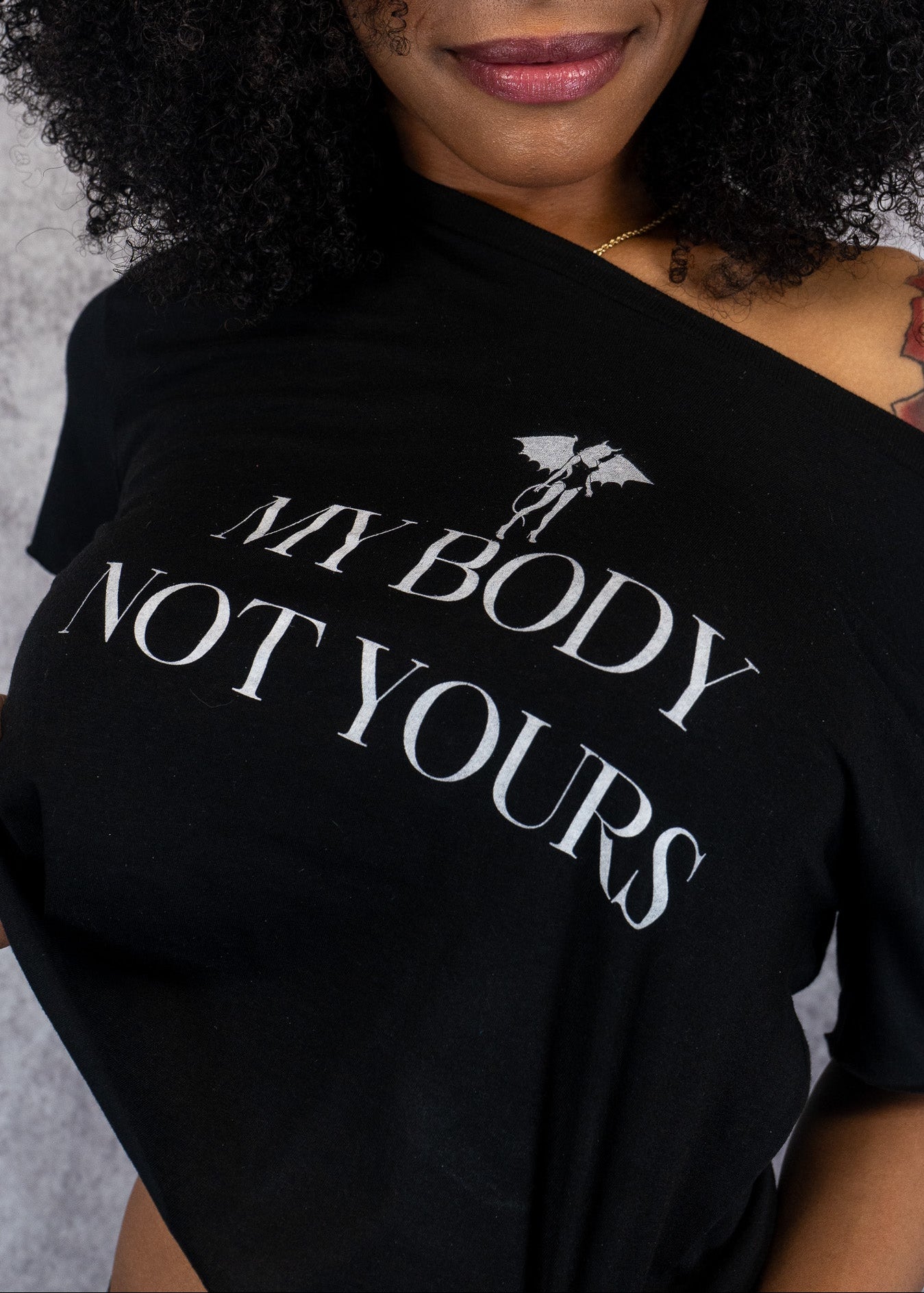 Woman wearing a DD black t-shirt with 'My Body Not Yours' text and graphic.