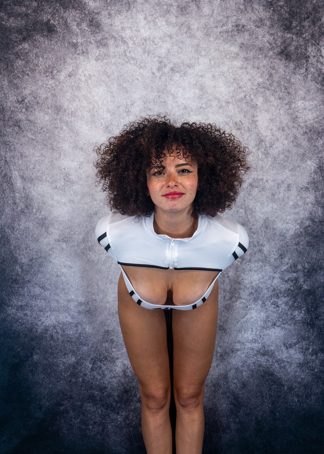 Person wearing a white outfit with black accents against a textured gray background